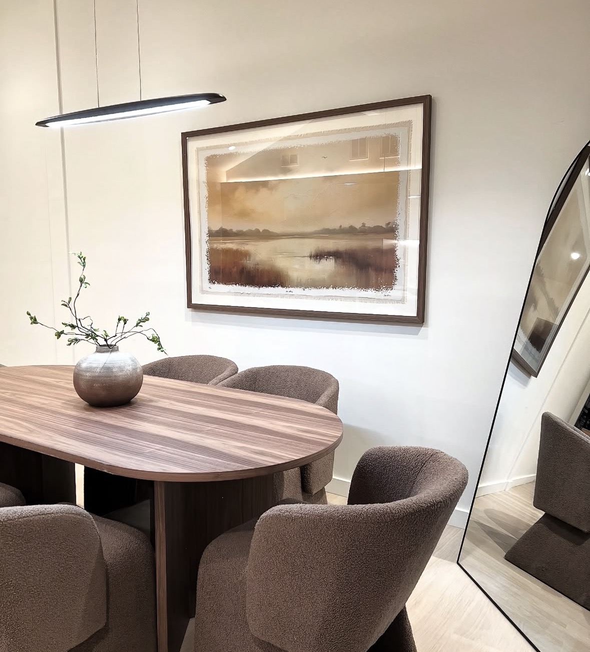 Walnut dining table with bouclé chairs and framed landscape